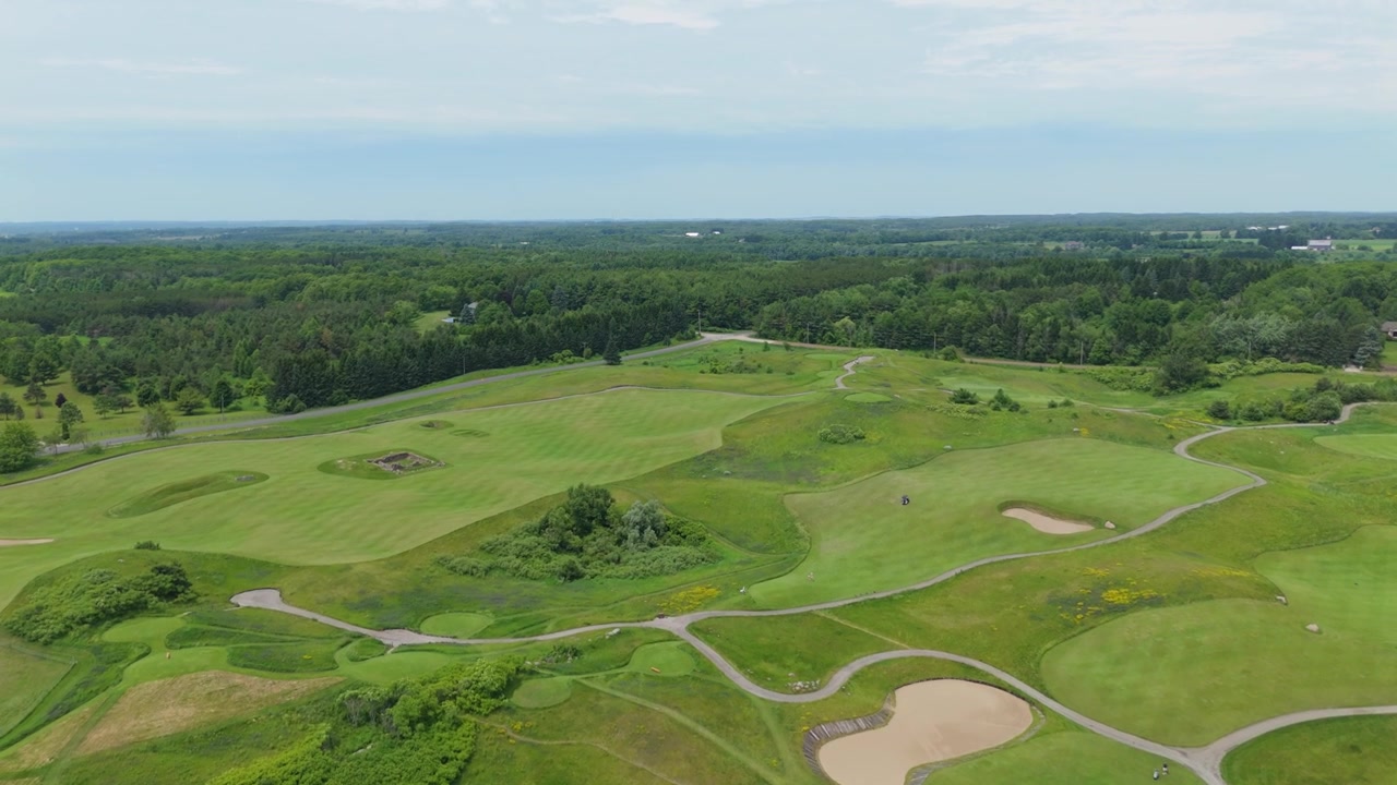 Gentle aerial move over rolling greens, sand bunkers, and winding cart paths at The Paintbrush course.