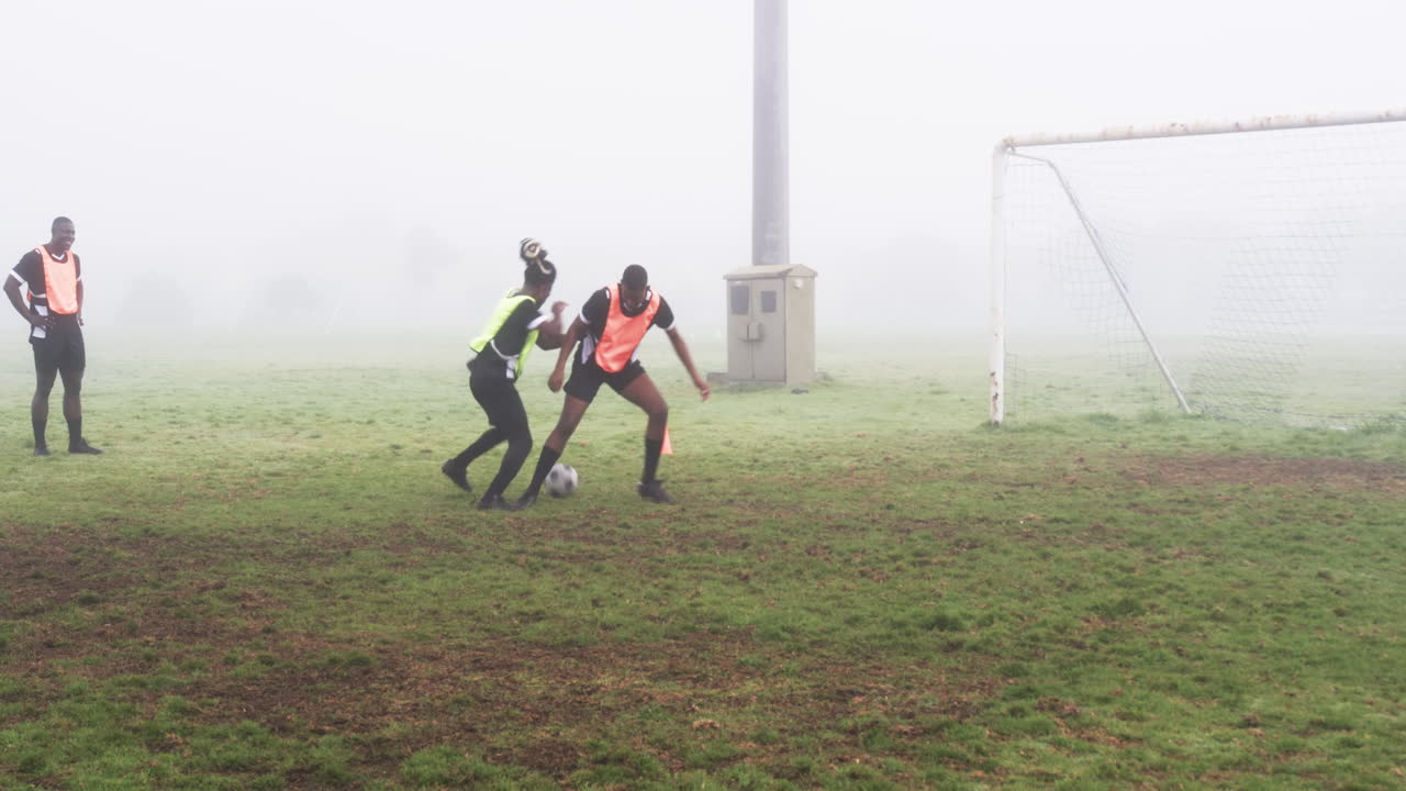 Soccer players practicing on foggy field, goalie diving to save ball