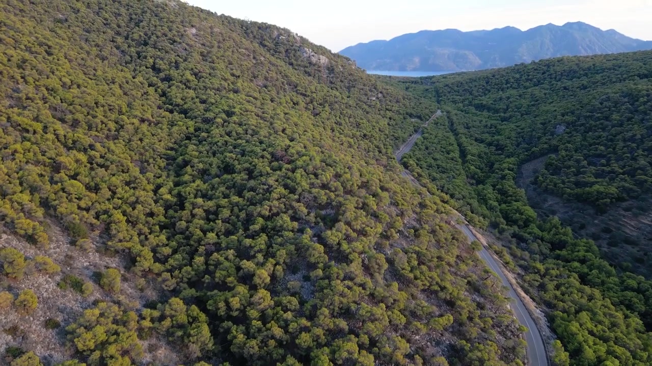 Bellissimo tilt up cinematografico con drone su strada che attraversa un'isola greca