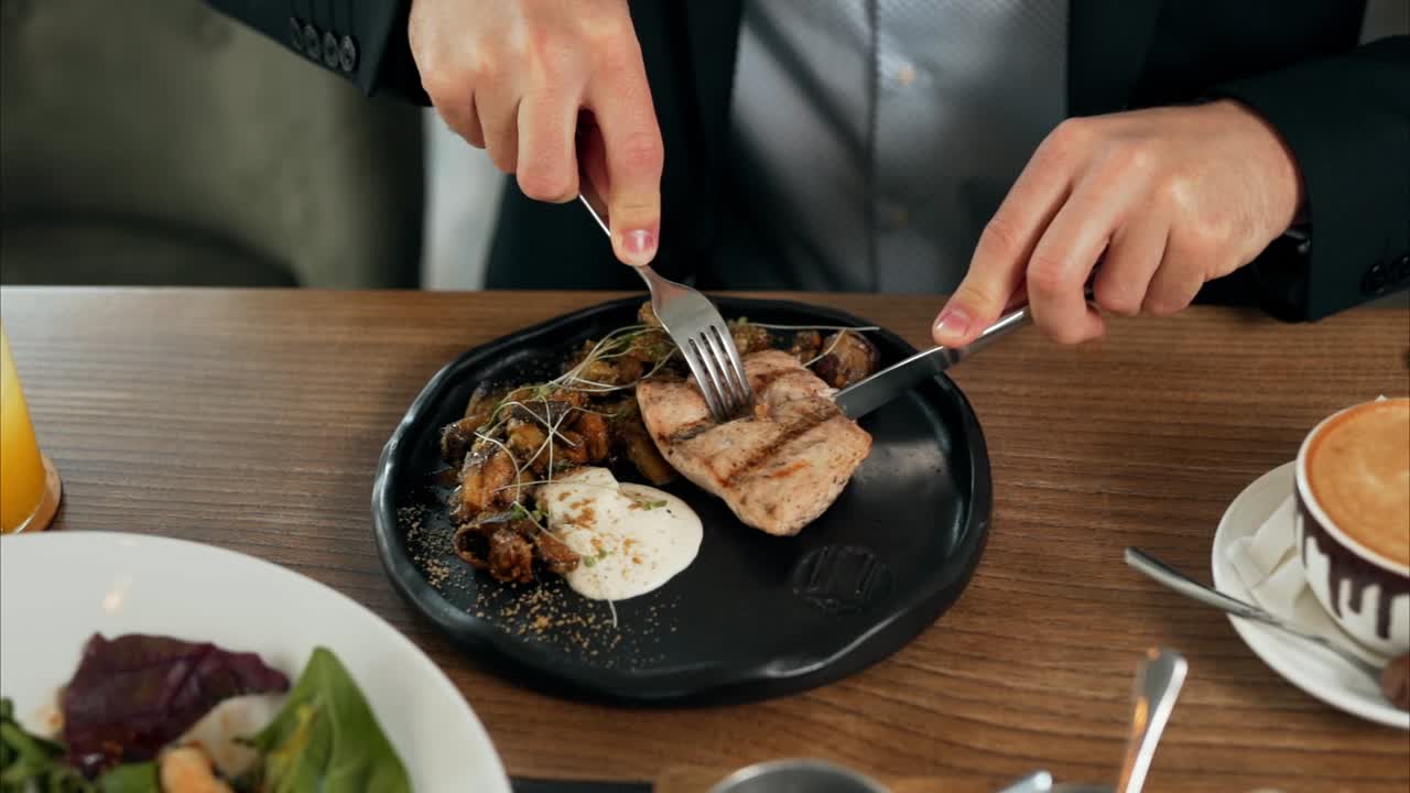 Close-up of male hands cutting steak