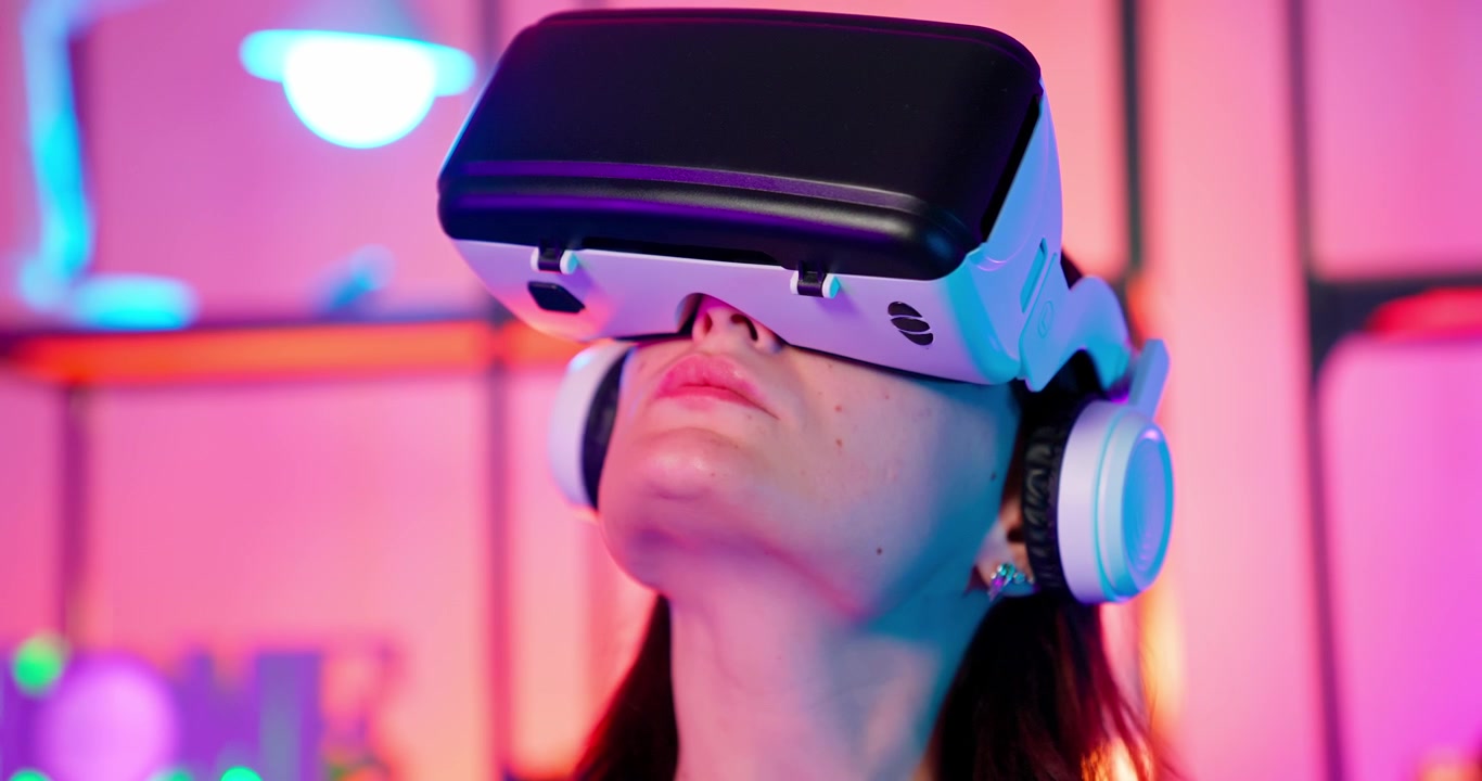 Giovane donna che gioca a un gioco VR con visore e controller sotto luci al neon