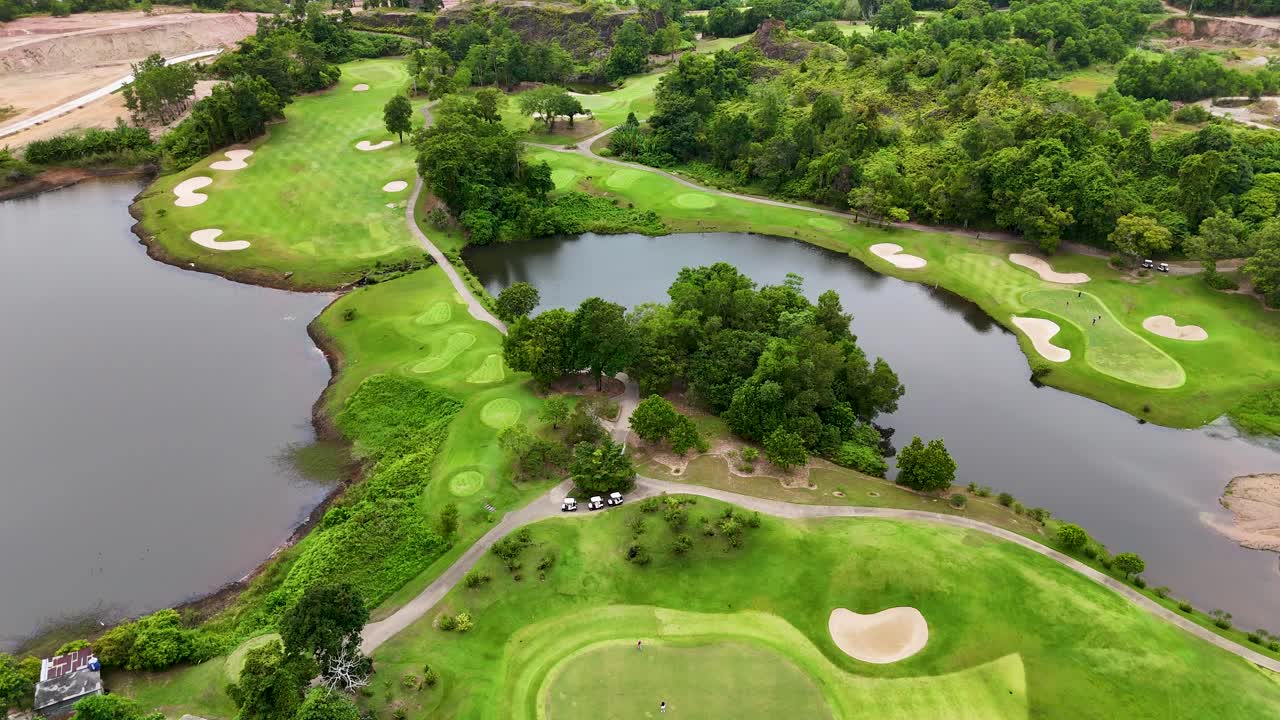 Aerial drone footage showcases the lush, green fairways and water features of a luxury golf course in Phuket, Thailand