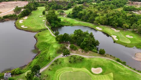 aerial drone footage showcases the lush, green fairways and water features of a luxury golf course in phuket, thailand