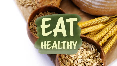 animation of eat healthy text banner against close up of variety of bread and grains