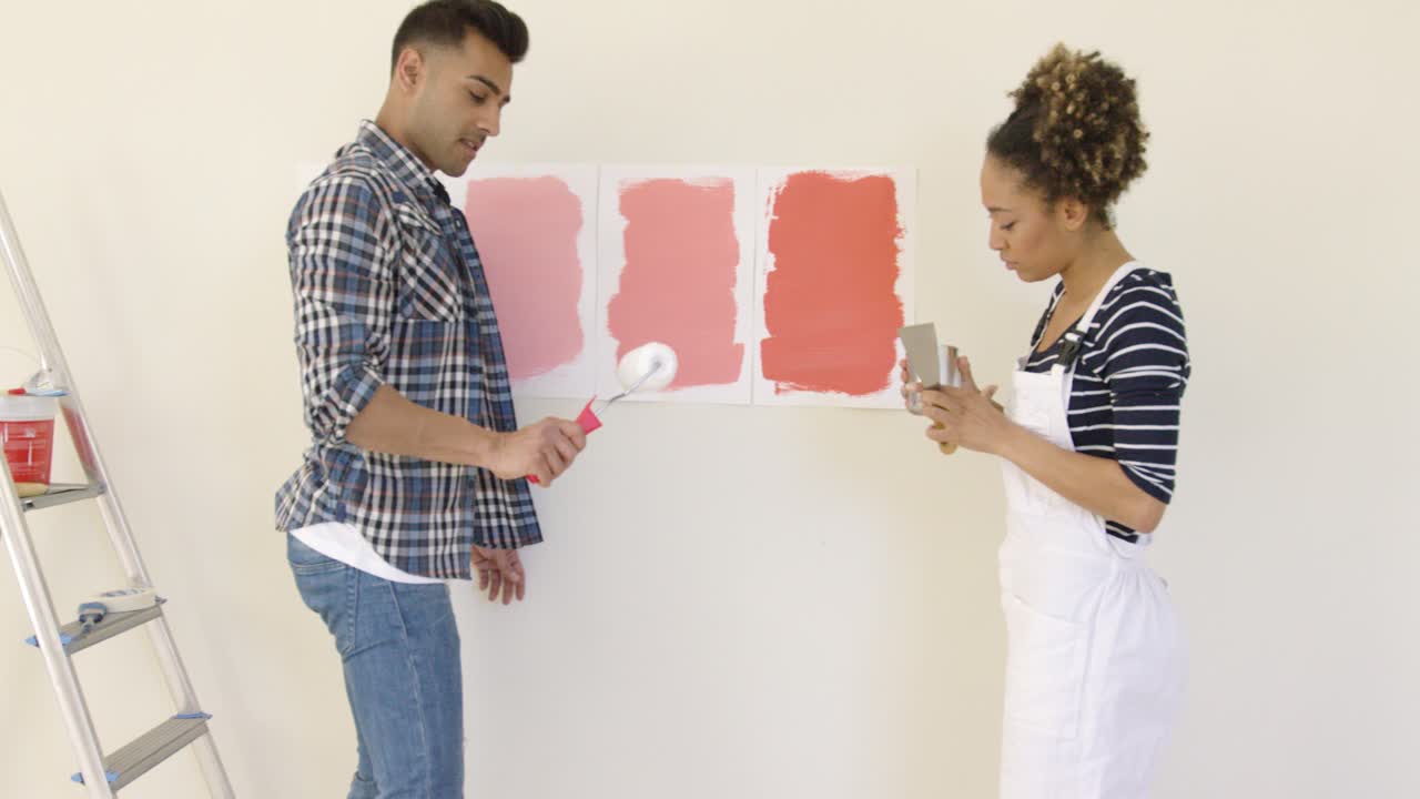 pareja joven riéndose eligiendo un color de pintura