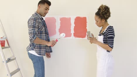 laughing young couple choosing a paint color