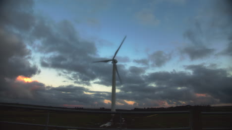 lone wind turbine spinning against golden hour cloudy sky, wide angle