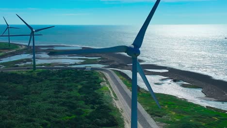 aerial orbit shot of rotating wind turbines along coastline in taiwan