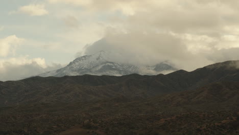 a timelapse of a beautiful arizona mountain with a rare snowfall, as clouds roll over the desert