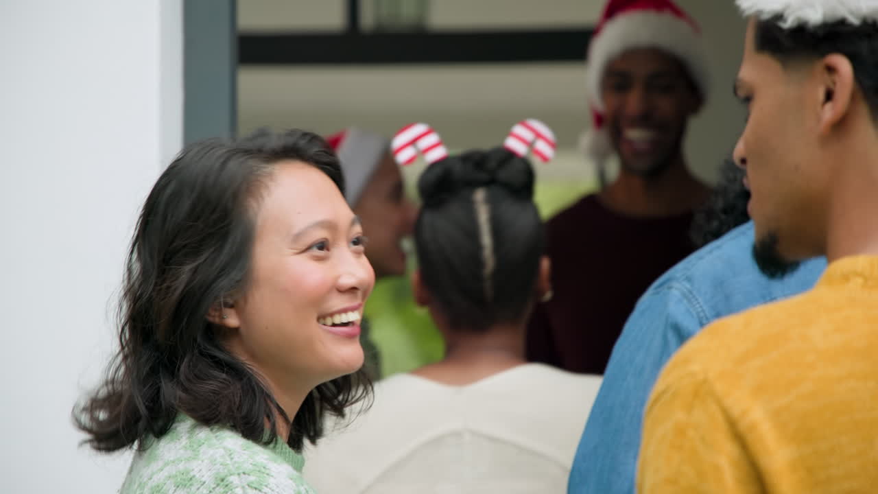 Young diverse friends celebrating Christmas at home, laughing and enjoying festive moments