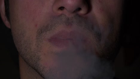 primer plano de la boca masculina adulta joven con rastrojo fumando e inhalando cigarrillos