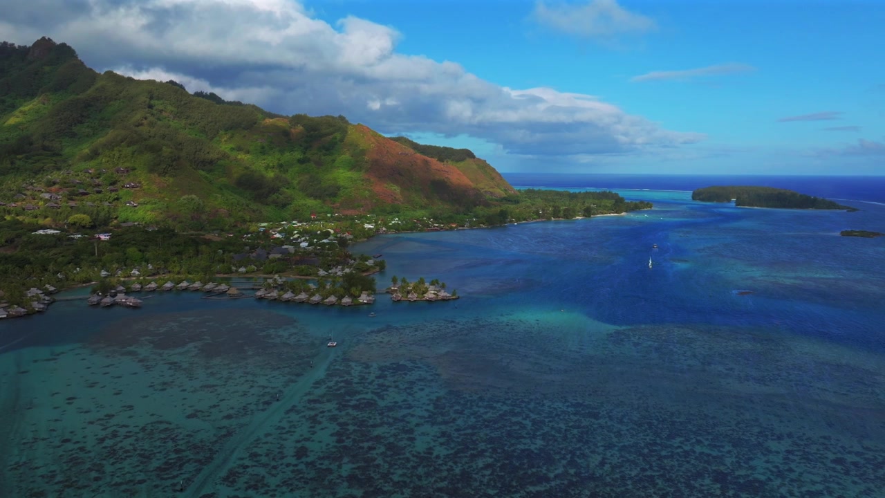 Cook's Bay Opunohu Bay shoreline Ta'ahiamanu Public Beach Bora Bora Moorea French Polynesia aerial drone bungalows over coral reef channel sailboats afternoon sunny blue sky forward pan up motion
