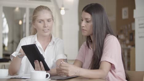 contenta donna bionda che tiene tablet e spiega i dati