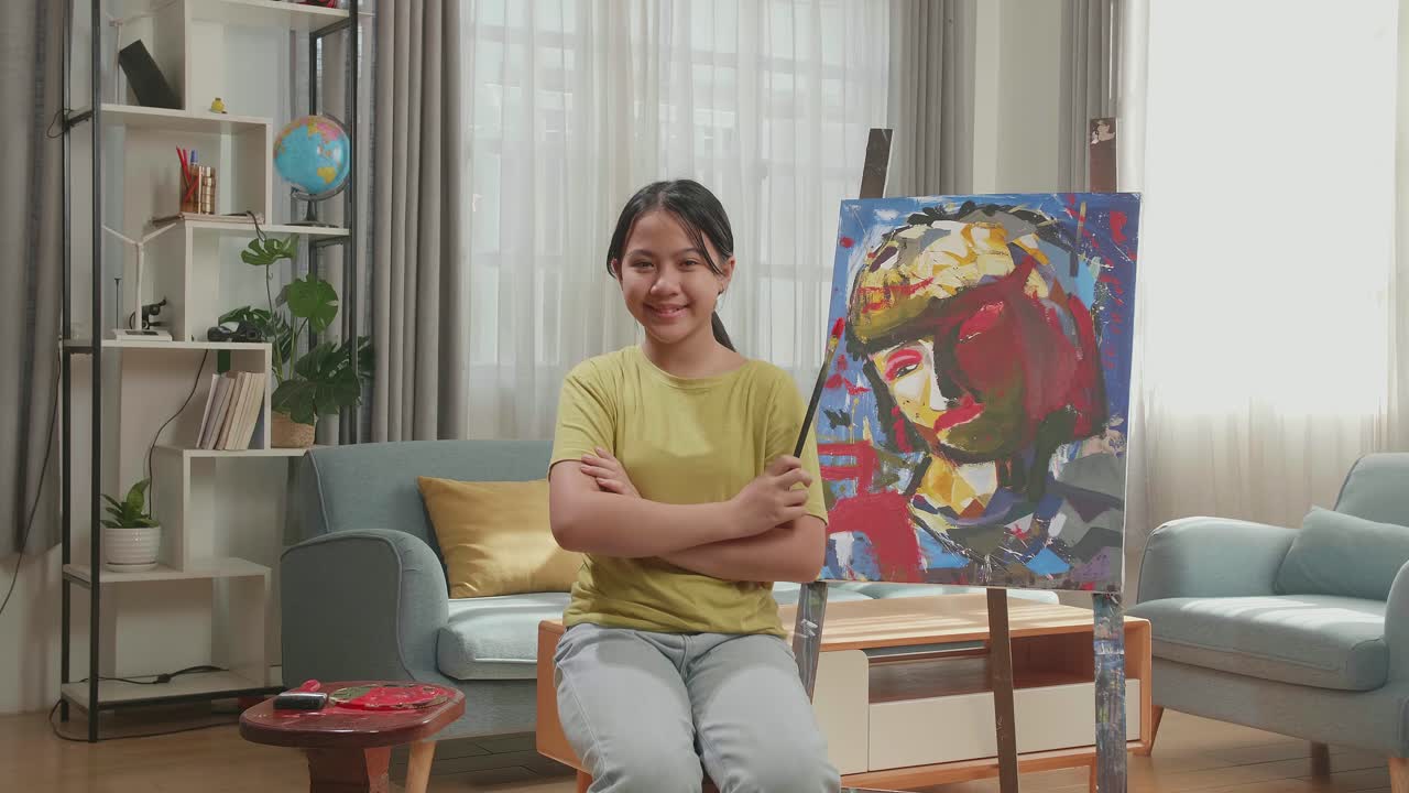 Asian Artist Girl Holding Paintbrush Crossing His Arm And Smiling After Finish Painting A Girl On The Canvas