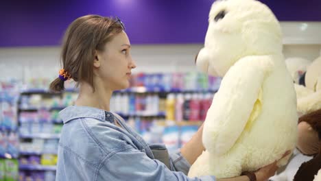 close up footage of the girl looking for the soft toys on the shelf in the supermarket. she is determined with a choice. shelf