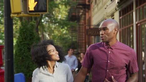 close up rear view of couple walking along street holding hands
