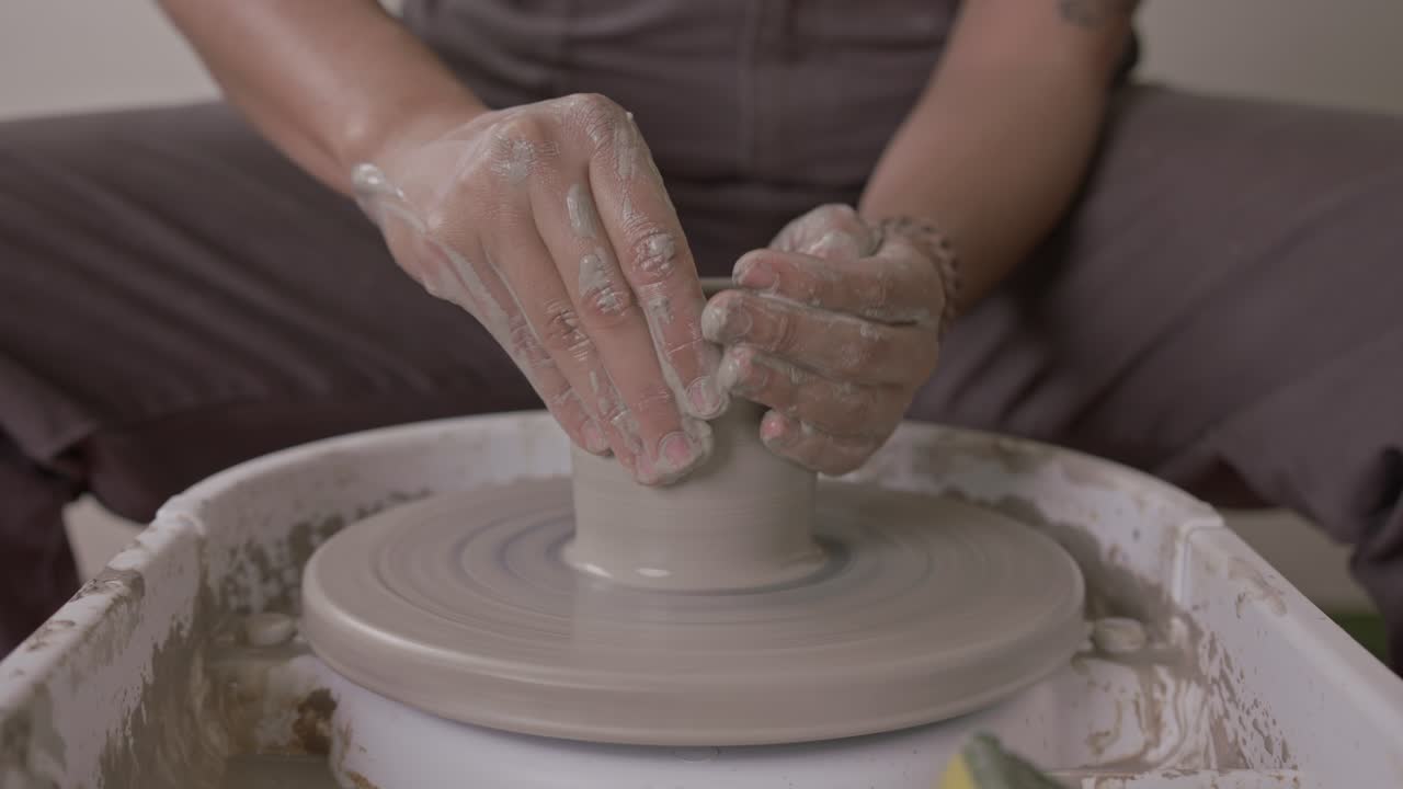 un alfarero experto moldeando hábilmente las paredes de una olla de arcilla húmeda en una mesa giratoria