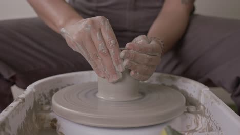 skilled potter deftly shaping the walls of a wet clay pot on rotating turntable