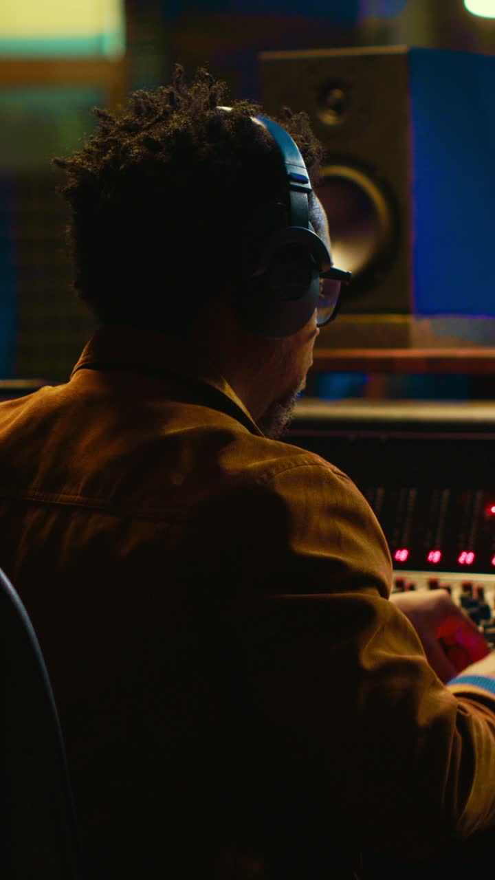 Produttore musicale che lavora alla consolle di missaggio in uno studio di registrazione