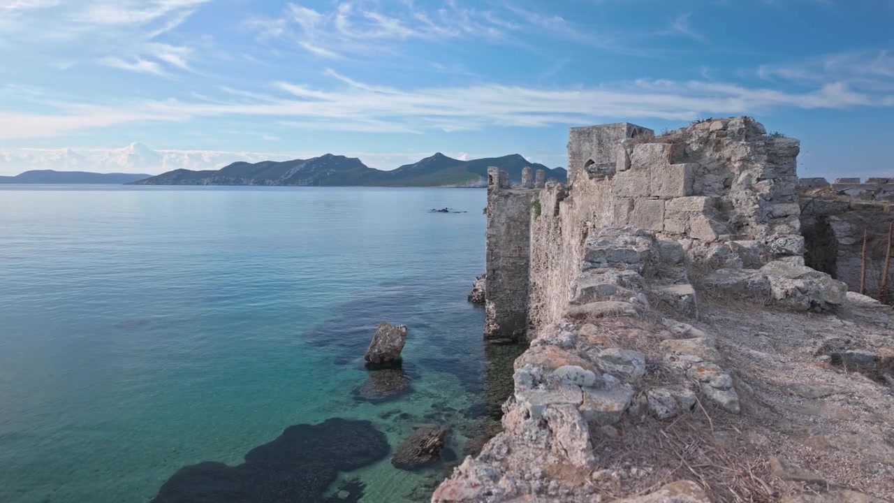Panoramica verso il basso dai bastioni di un castello medievale in rovina alla costa rocciosa mediterranea
