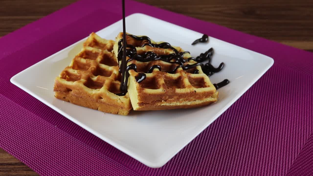 Calda de Chocolate Gotejando sobre Waffles Dourados em um Prato Branco