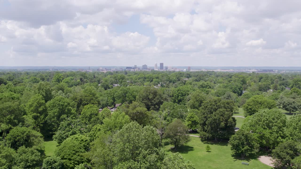 Drone shot of the Louisville, Kentucky skyline rising behind a green public park. Ideal for urban nature, tourism, and city lifestyle content.