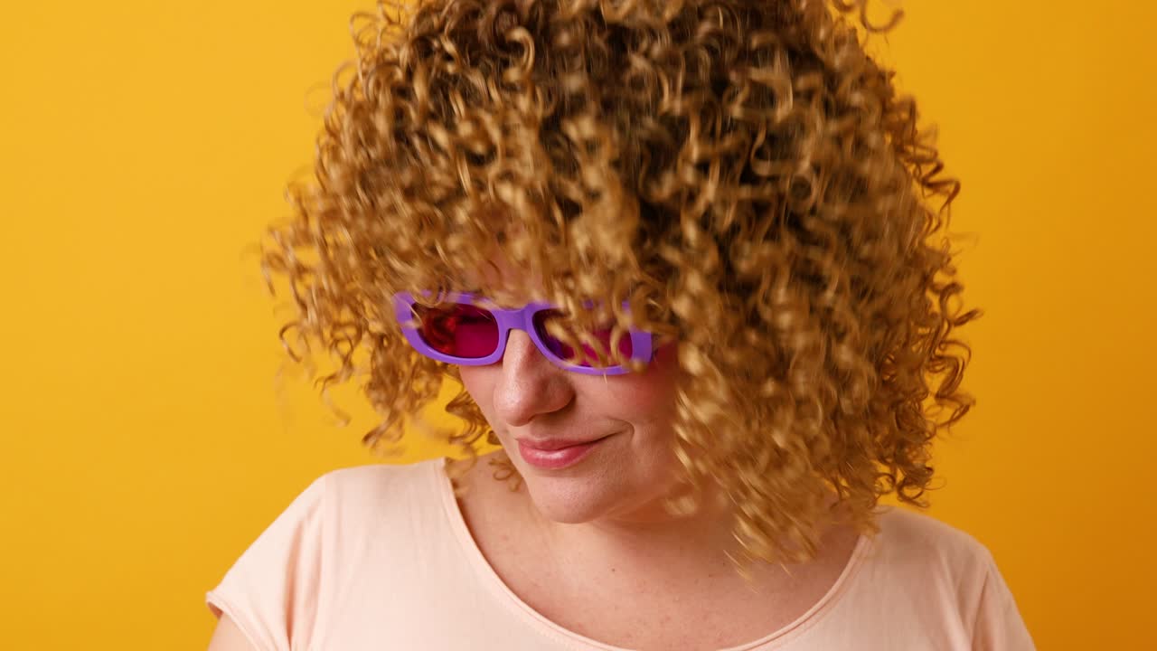 30대 여성, 곱슬머리, 춤을 추고, 노란색 배경에 음악을 들으면서 손을 들고, 즐거운 춤, 긍정적인 라이프 스타일.