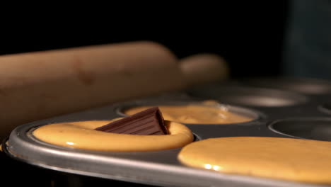 cuadrado de chocolate cayendo en la masa de pastel en la bandeja
