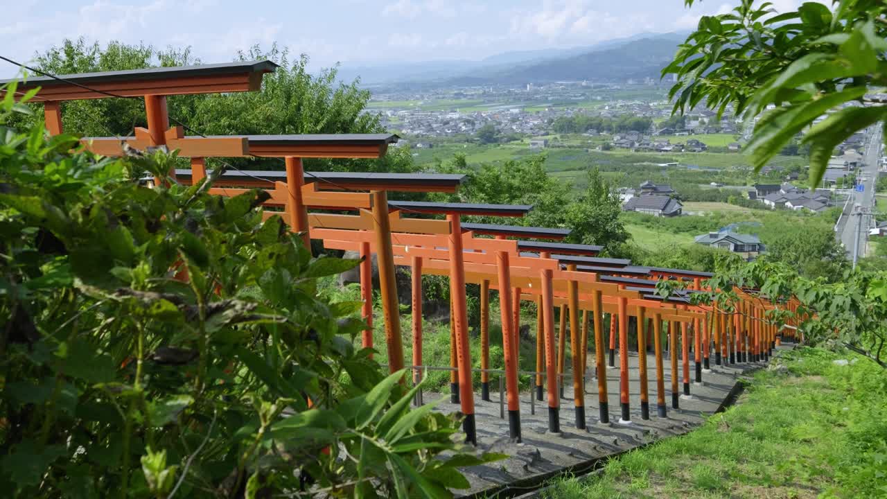 Cinematic panorama view over rural Japanese countryside with rows of red torii gates