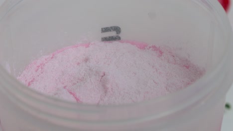 disparo estático de un agitador para la aptitud mientras que el delicioso polvo de suero de cereza se agrega para un batido refrescante para los deportes