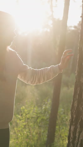 mujer toca el tronco de un árbol en un día soleado. amor y respeto por la vida silvestre al atardecer. dama con cabello largo y suelto se siente vacía y deprimida caminando en el aire fresco