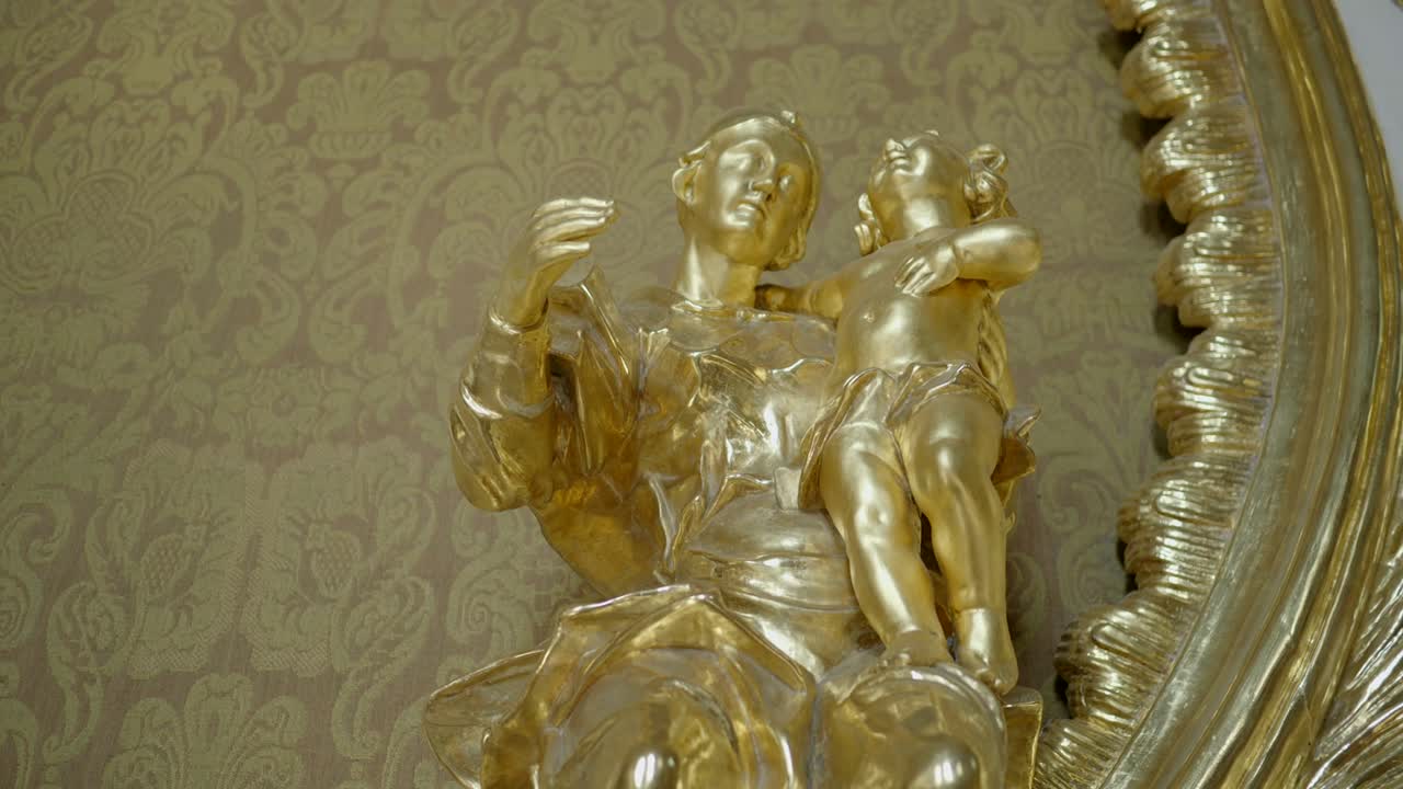 A close-up of a golden statue of a mother and child, which is part of the altar in the chapel of a Gothic castle