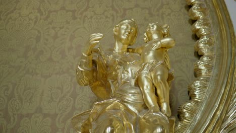 a close-up of a golden statue of a mother and child, which is part of the altar in the chapel of a gothic castle