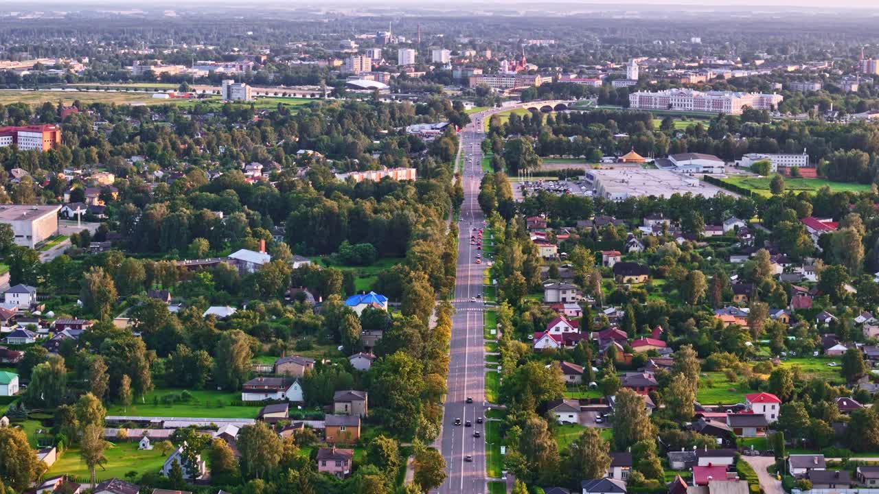 Aerial view of long tree-lined street in Jelgava, Latvia with evening traffic