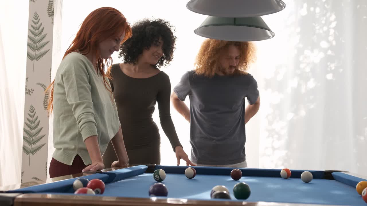 Friends watching man playing pool in game room on weekend