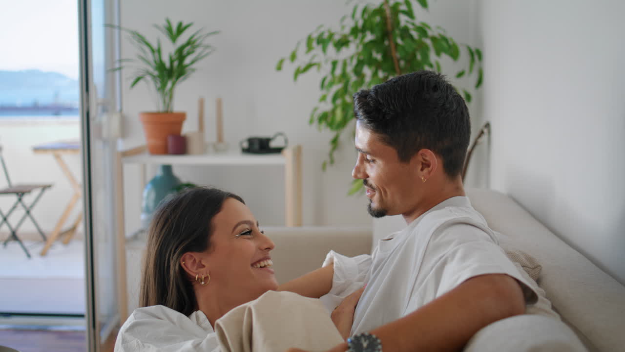 Funny spouses joking hotel closeup. Gentle man caresses wife relaxing soft couch
