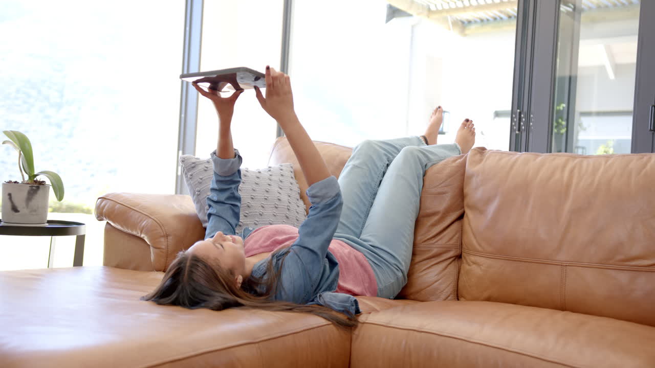 Reading book, girl relaxing on couch at home, enjoying leisure time, copy space