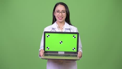 Young beautiful Asian woman doctor showing laptop