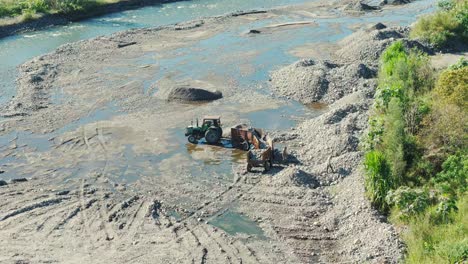 Aerial-view-of-a-machine-and-people-removing-stones-from-a-shallow-river-in-Tucumán,-Argentina