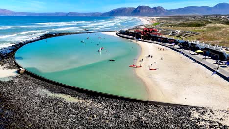 drone clip of a large tidal pool with a sandy beach and the coastline in the background