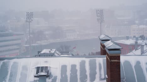 Fuertes-Nevadas-Sobre-Los-Tejados-De-Sankt-Hanshaugen,-Oslo,-Con-Luces-De-Estadio-Deportivo-En-El-Fondo