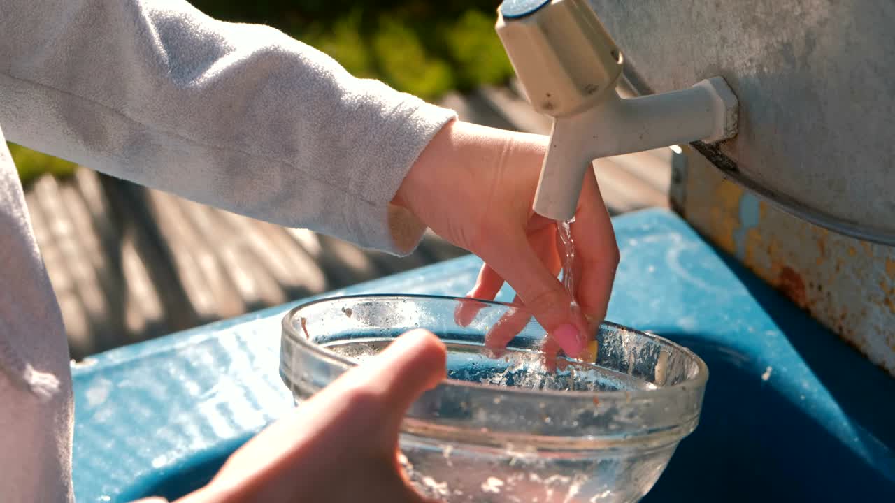 mujer lava un cuenco en un fregadero casero rústico al aire libre. manos de cerca.
