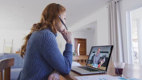 mujer caucásica usando portátil y auriculares de teléfono en videollamada con un colega masculino