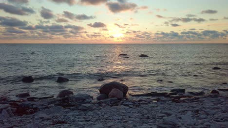Sonnenuntergang-An-Einem-Felsigen-Strand-Mit-Wellen,-Die-Ans-Ufer-Schlagen
