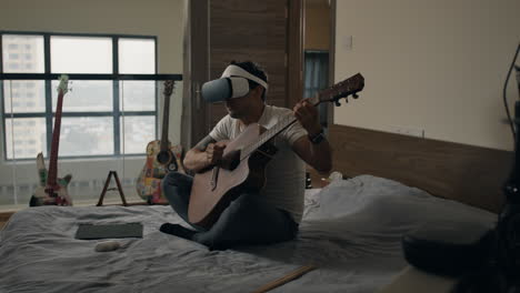 man plays acoustic guitar and sings while wearing vr headset in bedroom filled with musical instruments.
