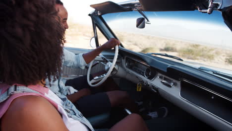 black couple in open top car on a desert highway, close up