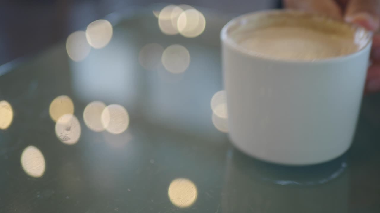 Close-up of a hand holding a coffee cup with a blurred background