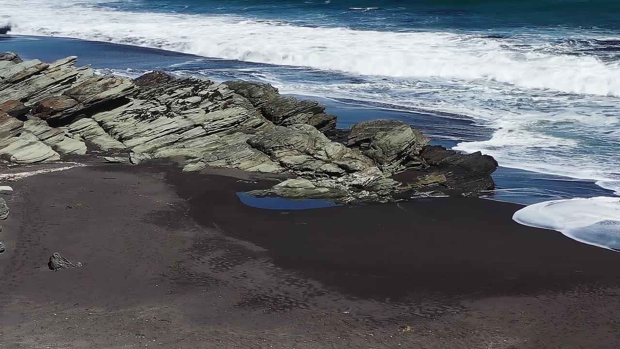 Le onde si infrangono sulla costa rocciosa di una spiaggia in Cile durante una giornata di sole