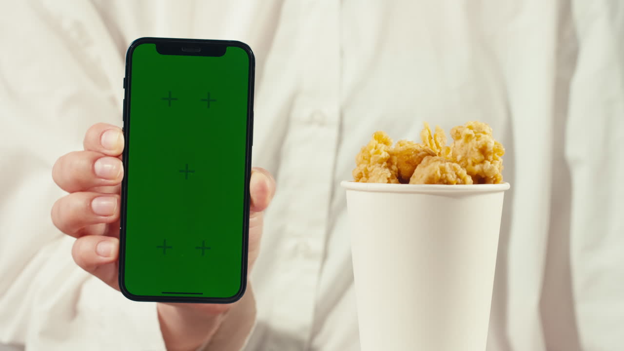 Woman holding phone next to popcorn