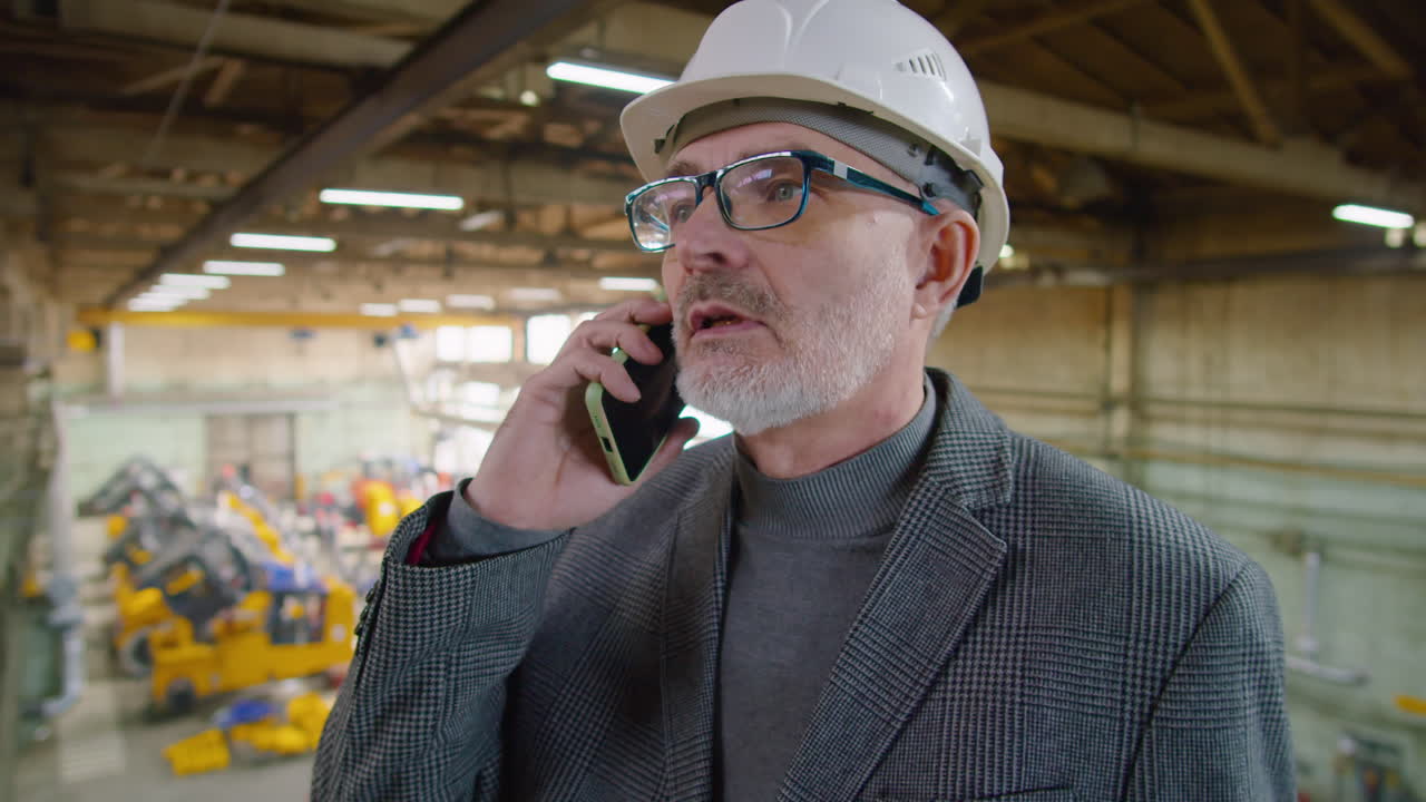 Senior Engineer Speaking on Cell Phone in Factory